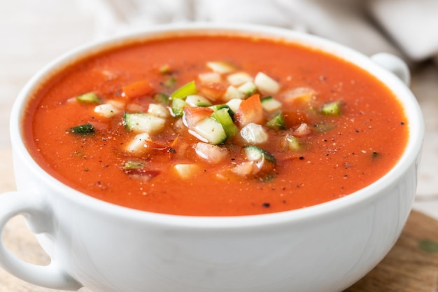 Traditional Spanish gazpacho soup in bowl on wooden table