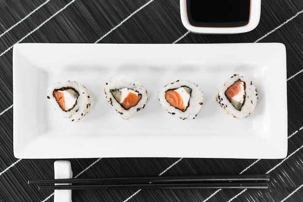 Traditional tasty sushi in white tray with sauce and chopsticks