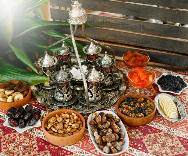 Традиционный чайный сервиз с антикварным чайным подносом, стаканами и сухими фруктами