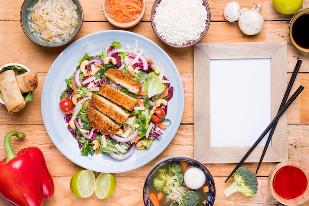 Free photo traditional thai food with blank picture frame and chopsticks on wooden table