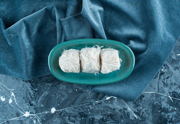 Традиционная турецкая сахарная вата на тарелке на полотенце, на синем столе.
