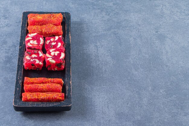 Traditional Turkish delights on a wooden plate , on the marble background.