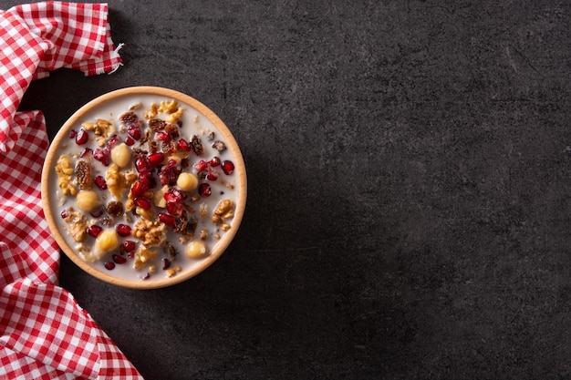 Traditional Turkish Noah's pudding in bowl on black slate background