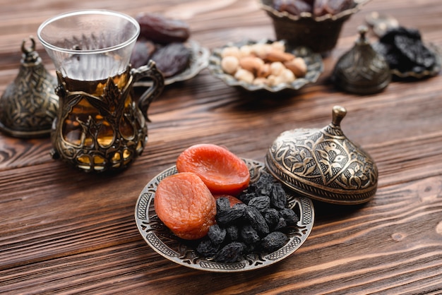 Traditional turkish tea and dried fruits on metallic tray over the wooden table