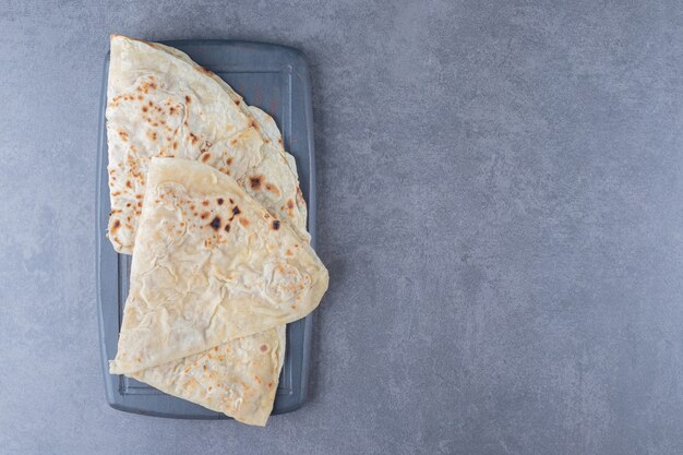 Traditional wheat lavash bread on the wooden tray on marble table.