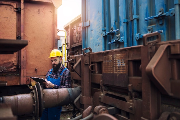 Free photo train maintenance railroad worker checking wagons and cars before departure