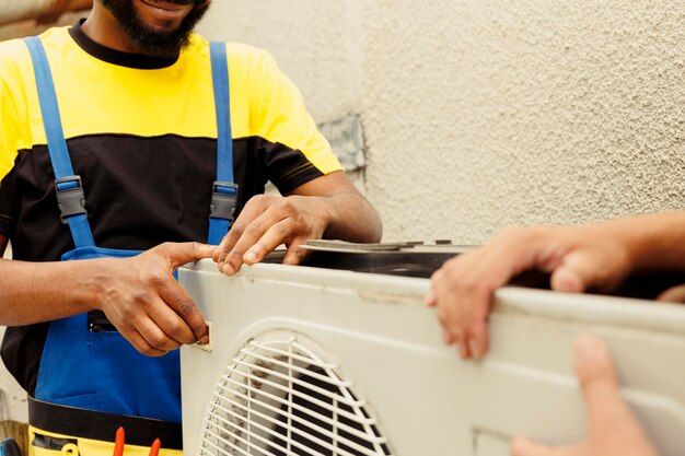 Trained engineer and certified technician opening up old faulty hvac system to replace it with new performant outside air conditioner after draining refrigerant and replacing ductwork