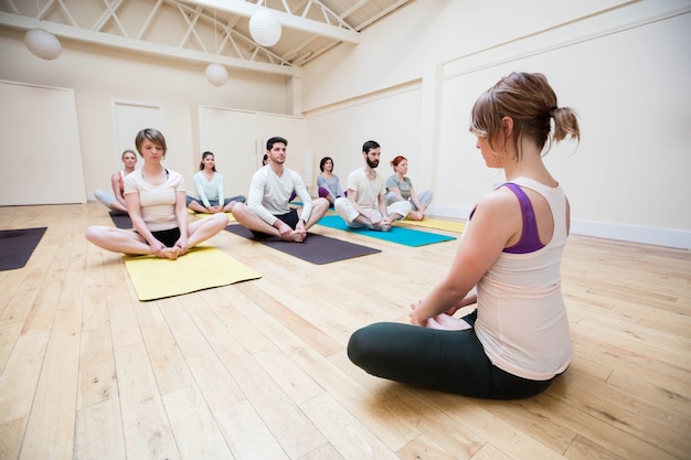 Trainer assisting group of people in meditation