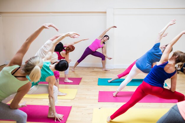 Trainer assisting group of people with stretching exercise