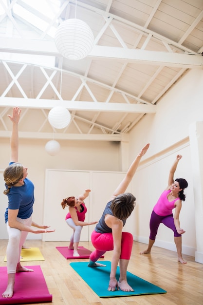 Trainer assisting group of people with stretching exercise