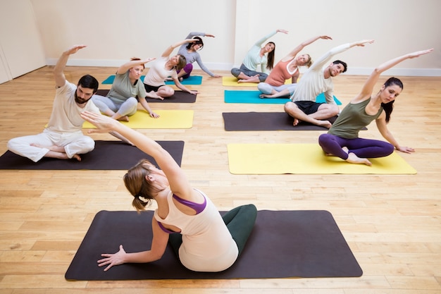 Trainer assisting group of people with stretching exercise