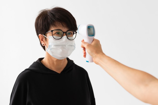 Free photo trainer scanning a woman temperature indoors