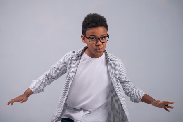 Free photo tranquil kid in spectacles dancing alone indoors