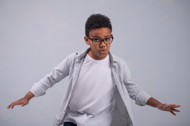Tranquil kid in spectacles dancing alone indoors