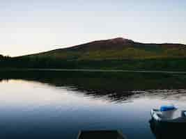 Free photo tranquil lake at the foot of a mountain against a bright sky