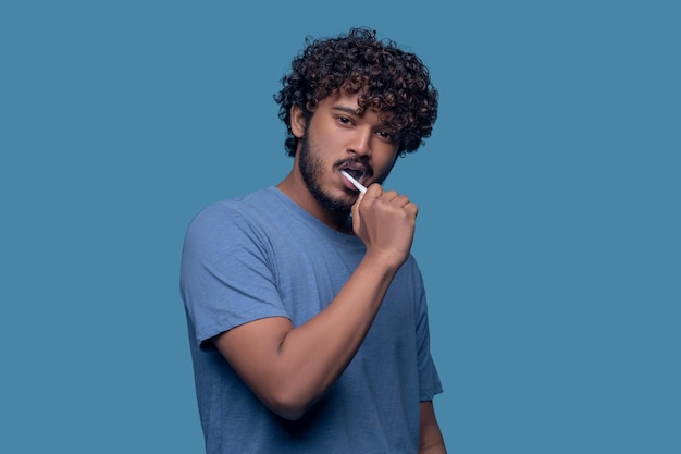 Tranquil young Indian man brushing his teeth