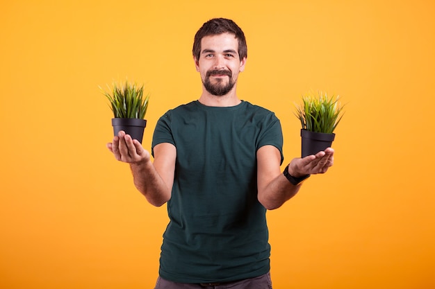 Free photo tranquility concept image of relaxed man holding two pots of grass in his hands