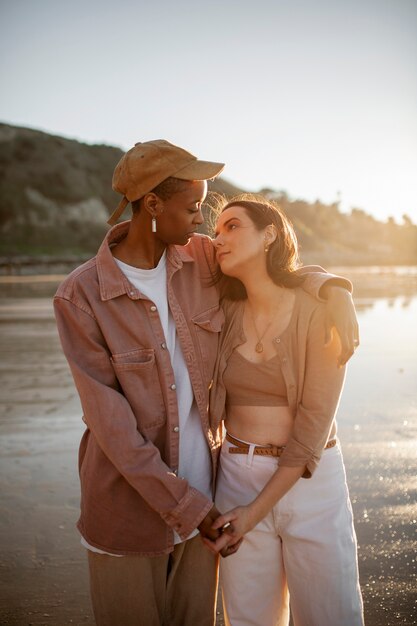 Trans couple holding each other on the beach at sunset