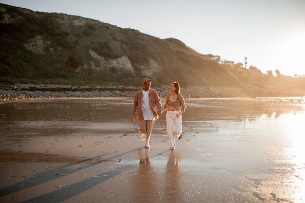 日没時にビーチを散歩するトランスのカップル