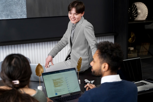 Foto gratuita persona trans che lavora in ufficio con i colleghi