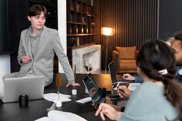 Foto gratuita persona trans che lavora in ufficio con i colleghi