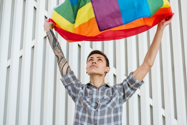 Foto gratuita transgender che tiene la bandiera arcobaleno