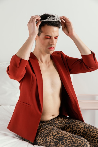 Persona transgender che indossa una giacca rossa e una corona