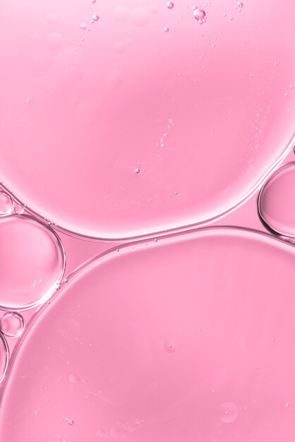 Translucent oil drops in water on soft pink blurred background