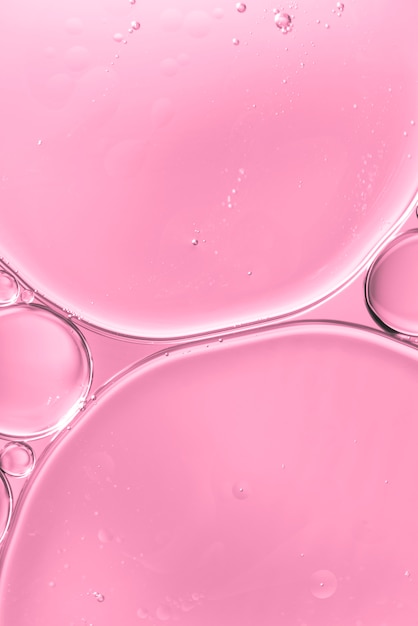 Прозрачное масло падает в воду на нежно-розовом размытом фоне