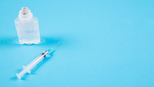 Transparent ampoules and syringe on blue backdrop