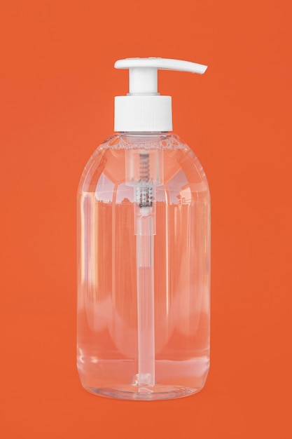 Transparent bottle of liquid soap on orange background