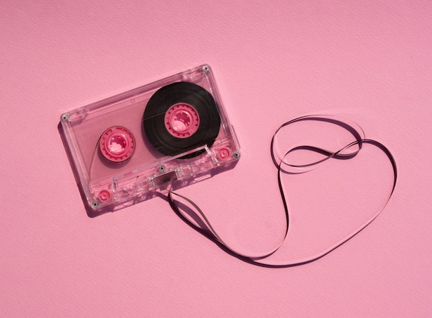 Transparent broken cassette tape on pink background