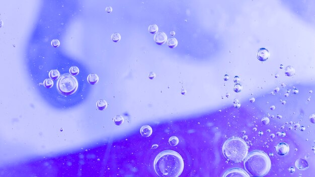 紫色の背景を覆う透明な泡