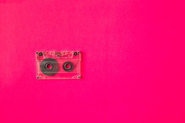 Transparent cassette tape on pink background