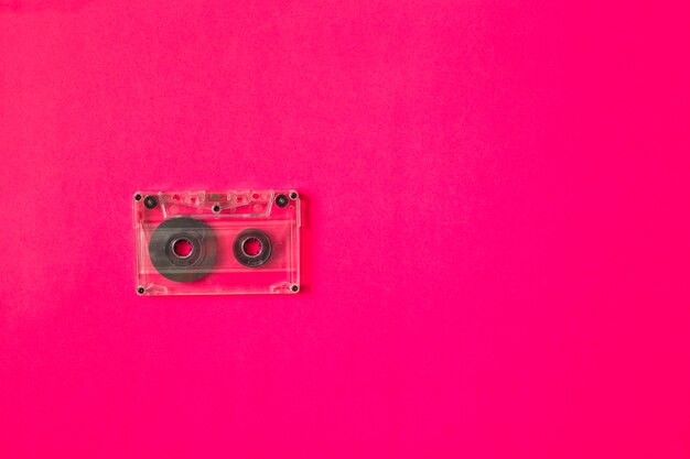 Transparent cassette tape on pink background