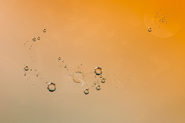 水っぽいオレンジ色の背景上の透明な液滴