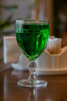 나무 테이블에 와인 음료가 있는 투명한 유리 유리에 밝은 녹색 음료