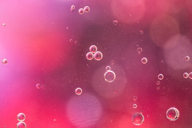 Прозрачные пузырьки масла на бордовом фоне