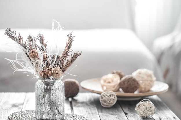 Transparent vase with dried flowers and plate with threads