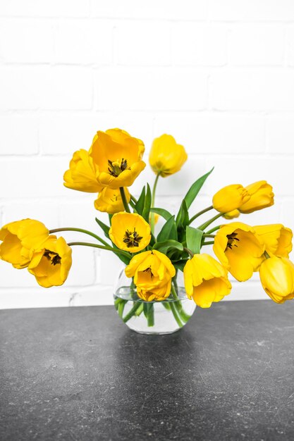 黄色いチューリップが付いている透明な花瓶