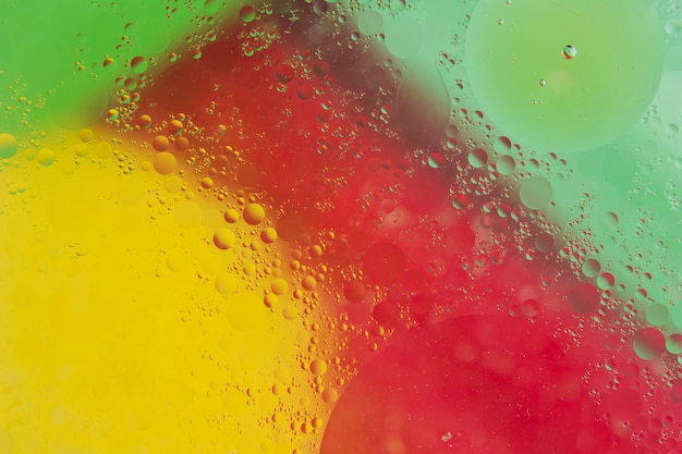 Transparent water drop over the red; yellow and green backdrop