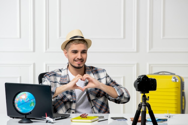 Travel blogger recording trip vlog on camera young handsome guy in straw hat sending love