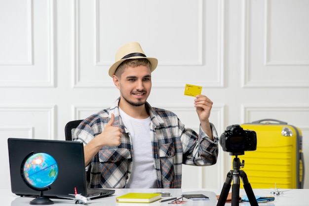 Foto gratuita il blogger di viaggio registra il vlog di viaggio sulla fotocamera giovane bel ragazzo con cappello di paglia con cartellino giallo