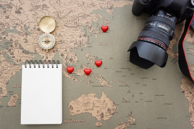 Travel composition with blank notebook, camera and red hearts