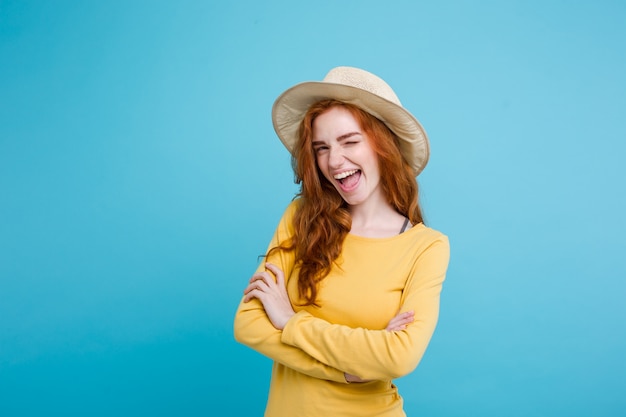 Travel concept - Close up Portrait young beautiful attractive redhair girl wtih trendy hat and sunglass smiling. Blue Pastel Background. Copy space.