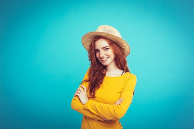 Travel concept - Close up Portrait young beautiful attractive redhair girl wtih trendy hat and sunglass smiling. Blue Pastel Background. Copy space.