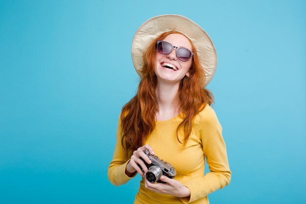 Концепция путешествия - закрыть Портрет молодой красивой привлекательной девушки redhair с модной шляпой и солнцезащитные очки улыбается. Голубой пастельный фон. Копирование пространства.