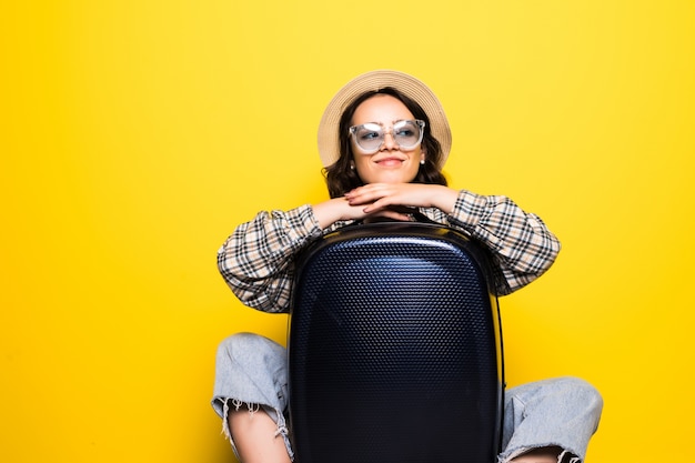 Концепция путешествия. счастливая туристическая женщина с солнцезащитными очками и шляпой в джинсовой одежде, готовая к путешествию, изолировала чемодан объятия.