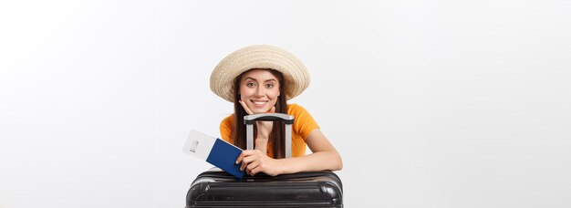 Travel concept studio portrait of pretty young woman holding passport and luggage isolated on white