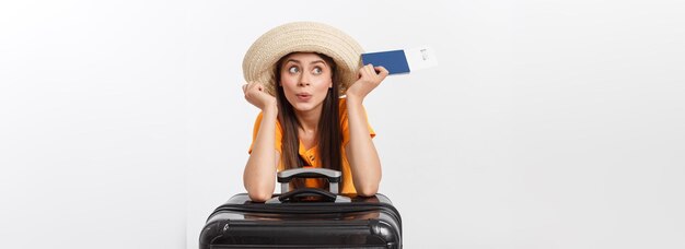 Ritratto in studio di concetto di viaggio di una donna abbastanza giovane con passaporto e bagagli isolati su bianco